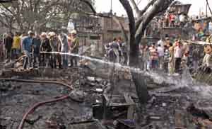 Fire personnel at work at a slum in Sadipur Katputli Colony of New Delhi that caught fire on Friday. 
