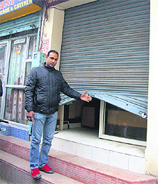 Ravi Kumar shows the broken shutter of his jewellery shop in Jalandhar on Friday.