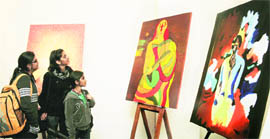 Visitors take a look at the paintings during a exhibition at the Kala Kendra in Jammu on Saturday