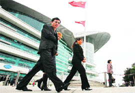 Mainland Chinese tourists in front of the Hong Kong Convention & Exhibition Centre with the Hong Kong and Chinese flags flying. A bitter family feud between Hong Kongers and mainland Chinese sparked by the northerners' increasing financial and political clout has led to an awkward debate about the former British colony's identity. Millions of mainland tourists and investors pour into Hong Kong every year, adding billions of dollars to the local economy. 