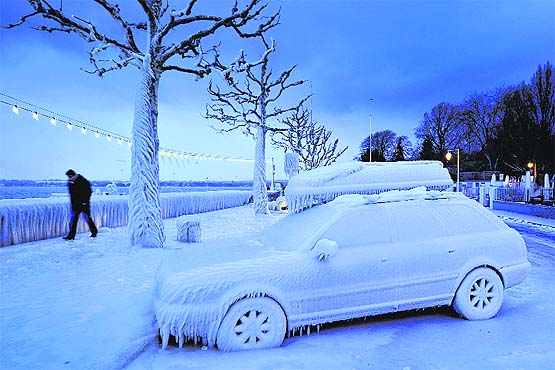 A man walks past a snow-covered car at Lake Geneva in Versoix city, near Geneva, on Sunday.
