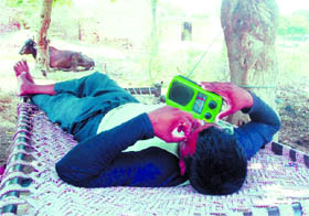 A man enjoys a warm day while relaxing on a cot and listening to songs on his transister in Bathinda on Tuesday.