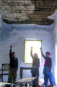 Schoolchildren point to the damaged roof of the building
