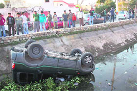 An overturned Mahindra Scorpio lies in a canal after it skidded off the road in the Trikuta Nagar area of Jammu on Tuesday.