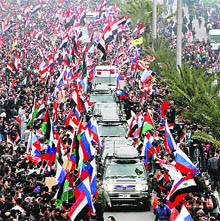 Pro-Syrian regime supporters wave Syrian and Russian flags as they cheer a convoy believed to be transporting the Russian Foreign Minister in Damascus
