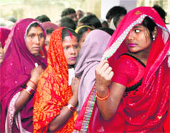 Women wait to cast their vote during the first phase of UP Assembly elections in Barabanki;