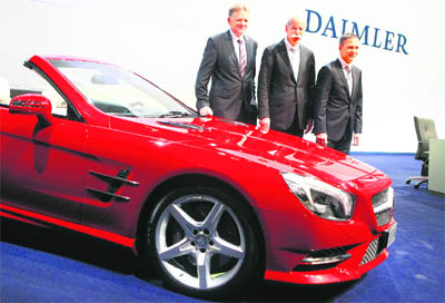 Dieter Zetsche (C), CEO of German auto giant Daimler AG, Andreas Renschler, head of the groups truck division, and CFO Bodo Uebber smile as they pose next to a Mercedes-Benz SL 500 for a picture prior to the company's annual news conference in Stuttgart on Thursday. Daimler, which owns the Mercedes-Benz car group, said it achieved record sales and profits in 2011, its 125th anniversary year. 