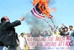 A protester holds a burning US flag during a protest against the drone attacks in Multan