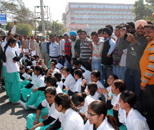 Students of the Adesh College of Nursing squat to block the Bathinda-Barnala road in protest against the college authorities on Friday. 