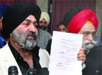Jasjit Singh (L), president of the Shiromani Akali Dal (Delhi-UK), and Sukhbir SIngh Kalra (R), senior vice- president, show a court order at a press conference in 
