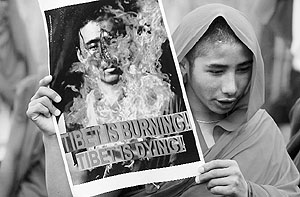 A Tibetan monk holds a poster depicting a burning monk during a rally in Siliguri.