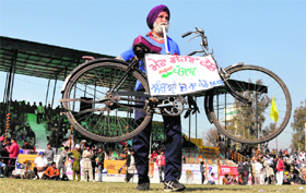 Gurnam Singh lifts a bicycle with the help of his teeth at Kila Raipur Rural Sports Festival near Ludhiana on Sunday.