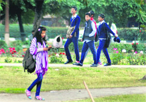 A girl walks around the Rose Garden as youths look on. 