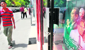 A man walks past a poster which shows ex-presidents Mohamed Nasheed (L), Abdul Gayoom (C), and the newly appointed president Mohamed Waheed Hassan Manik at a shop in Male on Monday. 