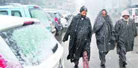 Pedestrians brave the snow in Srinagar on Monday.