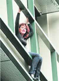 An employee of the Workers Housing Organisation threatens to jump from the office because her wages have been cut and she and her husband were threatened with layoffs, in Athens