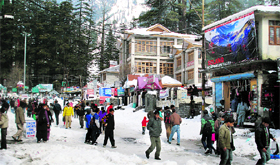 Tourists walk on the snow-covered Mall road in Manali on Wednesday.