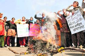 Women activists of the Istri Jagrti Manch burn an effigy of Punjabi singer Dilji at the Bhai Wala Chowk in Ludhiana on Thursday