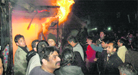 Residents gather outside the shops which caught fire in Lower Bazar, Shimla, on Thursday night.