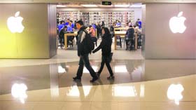 A couple walks past an Apple Store in downtown Shanghai on Saturday