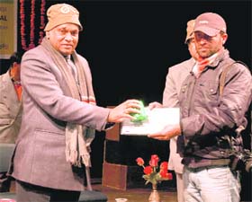 Chief Minister PK Dhumal presents an award to a winner of a birds photo contest at the Gaiety Theatre in Shimla on Saturday