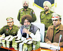 Policemen show the seized currency during a press conference in Ludhiana on Saturday