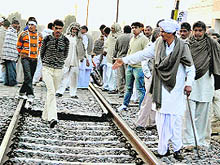 Members of the the All-India Jat Aarakshan Sangharsh Samiti block the railway track at Mayyar village in Hisar district on Sunday