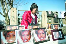 A woman organises pictures of Whitney Houston for sale during her funeral service in Newark.  Reuters