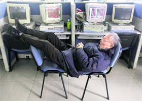 An investor sleeps on chairs next to computers showing stock information at a brokerage house in Wuhan, Hubei province, on Monday