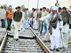 Members of the All-India Jat Aarakshan Sangharsh Samiti walk on the railway lines at Mayyar village in Hisar disrict on Monday.