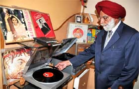 Baldev Singh Kamal plays a record on a gramophone at his residence