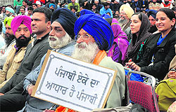 An elderly man holds a placard during the International Mother Language Day in Jalandhar on Tuesday