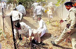 A farmer gets stuck in a fence as he tries to run away during a lathi charge in Gandhinagar on Thursday