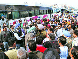 A policeman tries to pursuade protesting PRTC employees to lift a road blockade near the Rajpura bus stand on Thursday