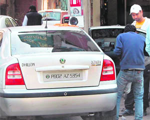Mechanics fit black films on windowpanes in cars in Amritsar. 