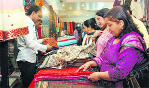 Women have a look at various varieties of silk at an Indian textile exhibition in Dehradun on Thursday