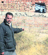 The factorys owner points towards the boundary wall which was broken by thieves to gain access to the unit. 