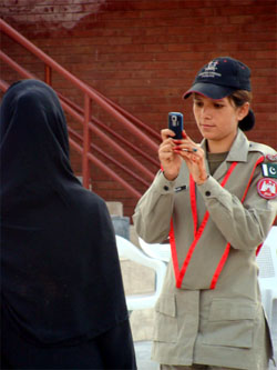 Amidst aggressive gestures by the Pakistani Rangers towards the BSF soldiers during the retreat ceremony at Hussainiwala border post in Ferozepur, a woman Ranger on Sunday clicks photograph of a visitor on their side of the border with India in the background.