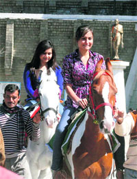 Girls enjoy a horse ride on a bright sunny day in Shimla on Sunday. 