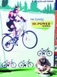 An old man sits in front of a hoarding on the concluding day of Bike Expo in Ludhiana. 