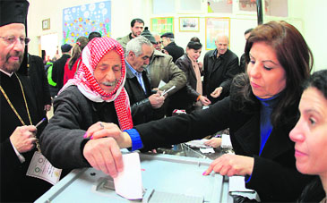 An official helps a man to vote at a polling station in Damascus on Sunday
