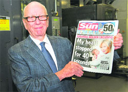 News Corporation Chairman and CEO Rupert Murdoch holds the first edition of The Sun on Sunday as it comes off the press at Broxbourne