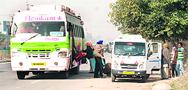 Passengers get off a bus near Kharar before being shifted to an auto-cab as the bus sans permit to enter Chandigarh.