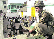A securityman on vigil as voters wait in queues during the sixth phase of the Uttar Pradesh Assembly elections in Muzaffarnagar on Tuesday.
