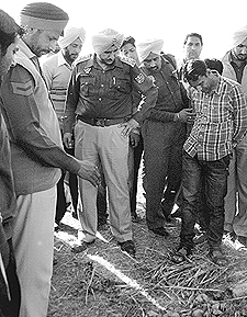 Policemen inspect the site where a man was murdered at Tiur village in Kharar.