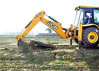 A bulldozer dismantles a road in an unauthorised colony near Ludhiana on Thursday