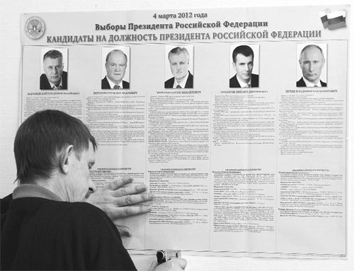 An employee fixes a poster displaying the five presidential candidates for the upcoming presidential elections in Moscow on Saturday. 