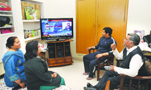 his opponent BJP's Manoranjan Kalia watches a news channel with his family at his residence in Jalandhar on Monday. 