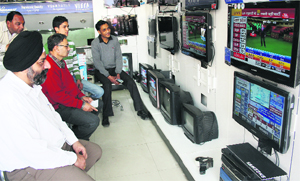 People watch the election results at a shop at Paltan Bazaar in Dehradun on Tuesday. 