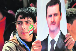 A Syrian demonstrator holds a portrait of President Bashar Al-Assad during a pro-regime rally in Damascus.